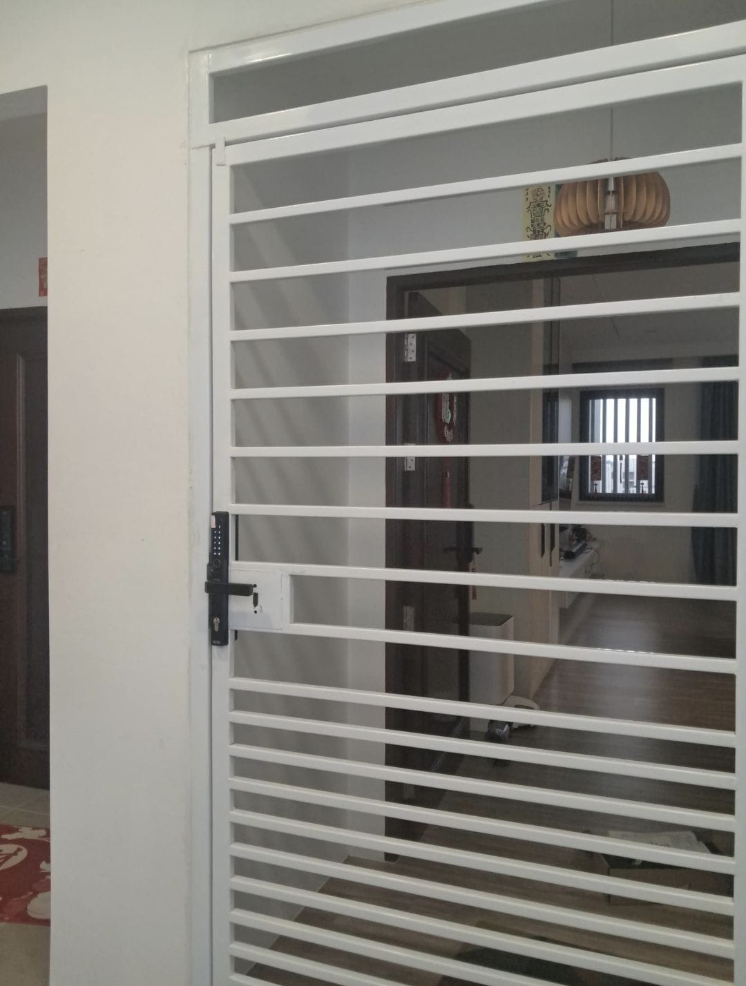 A smart digital lock fitted on a white metal grill door in a Kuching home